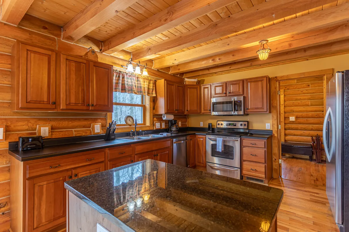 The kitchen boasts rich wooden cabinetry, sleek granite countertops, and state-of-the-art stainless steel appliances, all bathed in natural light from a nearby window. The functional layout invites guests to gather and cook together.